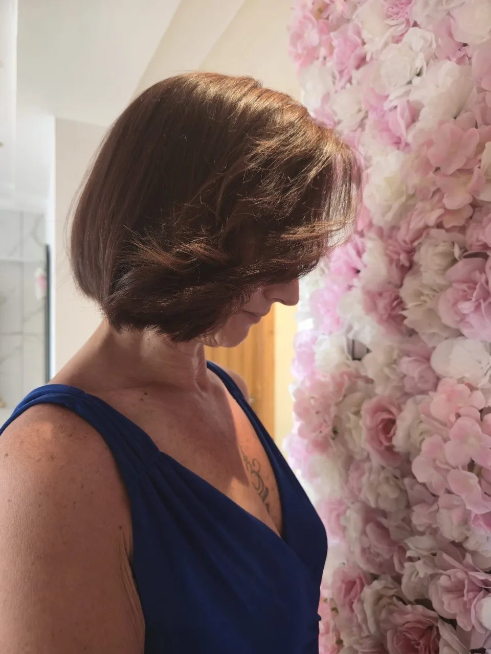 A freshly cut chestnut bob styled by the flower wall